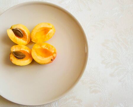 on the table is a plate with slices of apricot. core inside apricotの写真素材