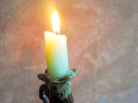 a burning candle stands in front of a pink wallの写真素材