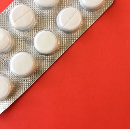 White pills on a red background. On a green background. View from above. Space for text.