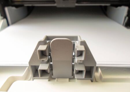 space for paper on the printer. Closeup of a part of a printer with white paper.