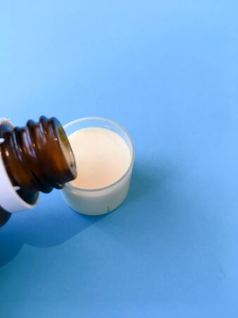 Bottle witBottle with liquid medicine. Transparent brown bottle and white liquid medicine.h liquid medicine. Transparent brown bottle with a cap.の写真素材