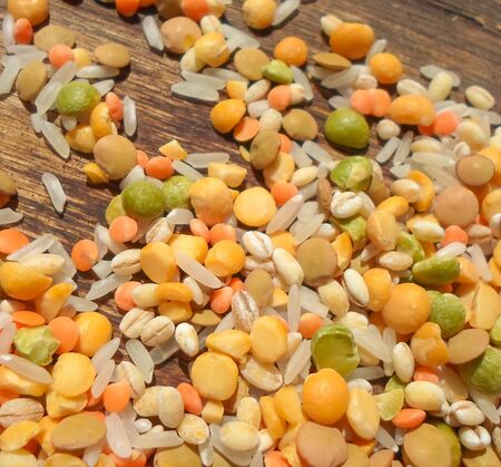 Colorful mixed cereals and legumes: rice, peas, lentils and pearl barley on a wooden background....
