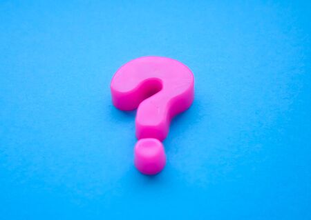 pink question mark located sideways on a blue background with copy space in a conceptual imageの写真素材