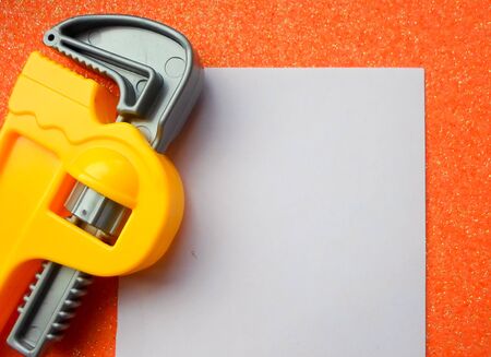 toy tools, wrench and others on an orange background. white sheet of paper place for textの写真素材