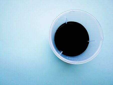 cup with liquid medicine. Transparent brown bottle and black liquid medicine.の写真素材