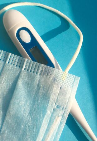 medical mask and thermometer on a blue background. protection against viruses and harmful bacteria. health conceptの写真素材