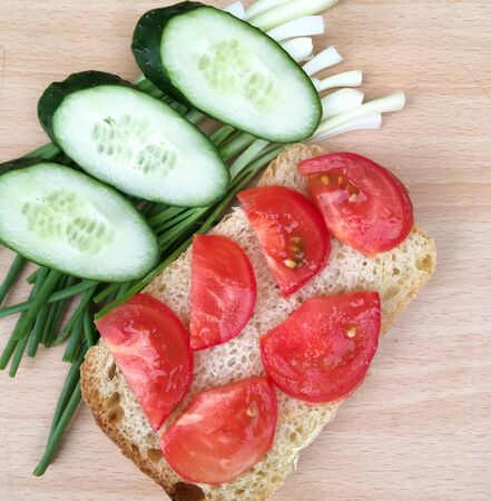 sandwich with bread with tomatoes and cucumbers and onions on a wooden table. healthy breakfast for every dayの写真素材