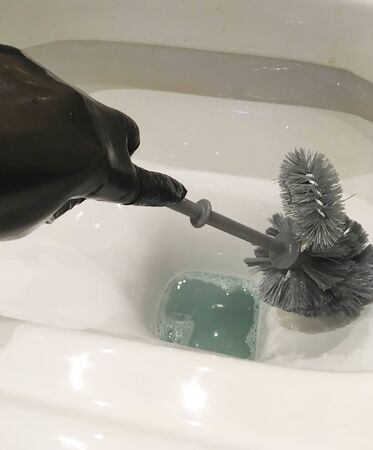 Wash a white toilet, a woman's hand in black gloves and with a brush. Daily cleaning of the bathroom toilet cleaningの写真素材