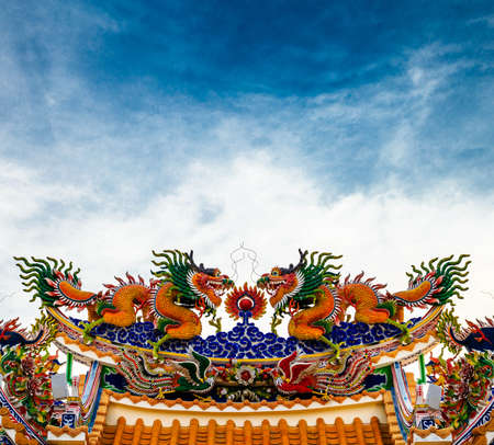 Chinese dragon statue on roof with blue skyの写真素材