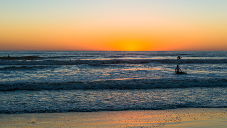 Surfers on the waves. Sunset over the ocean in San Diego. Coast southern California.の写真素材