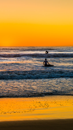 Surfers on the waves. Sunset over the ocean in San Diego. Coast southern California.の写真素材