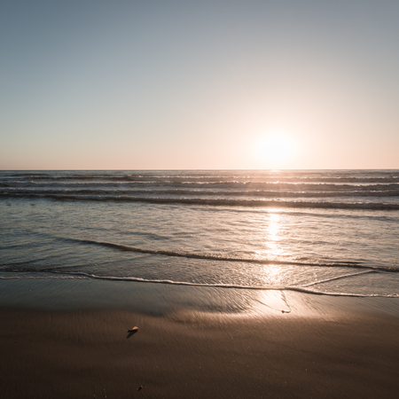Sand beach and ocean surf is painted in the colors of the setting sun. Coast of California.の写真素材