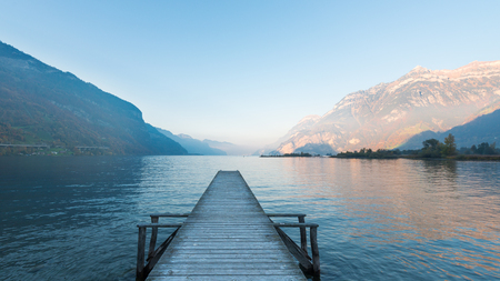 Wooden pier on the lake. Sunset in pastel colors. Mountains in the background.の写真素材