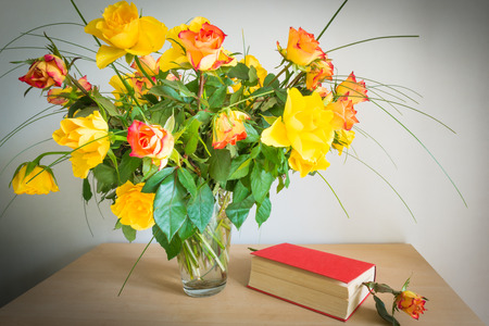 Bouquet of roses. Nearby is a book bookmark with flower roses. Selective focus.の写真素材