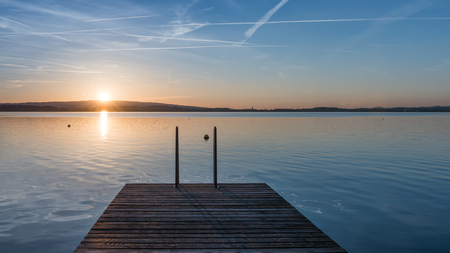 Relaxing quiet evening on the lake. Setting sun is reflected in water. Switzerland.の写真素材