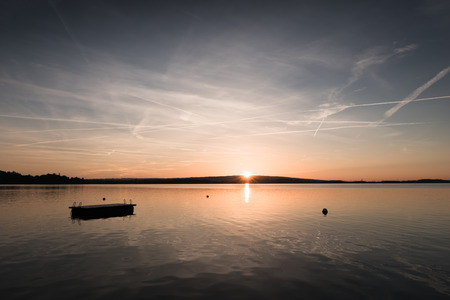 Sunset on the lake. Magnificent colors of the sky reflected in the water. Board for diving.の写真素材