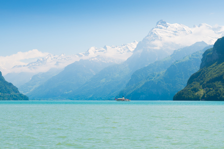 Grandiose mountain landscape. Mountain tops in the snow. Steamship floats on the lake.の写真素材