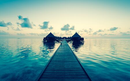 Panorama of tropical island.  Turquoise water lagoons, coral reefs visible. Sunrise sky and clouds painted in pink. Tourist Resort Deluxe. Maldivesの写真素材