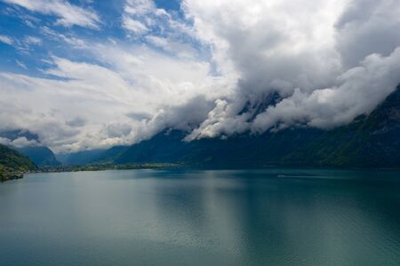 Impressive clouds over the mountains. Dramatic Sky.  Lake between the Swiss Alpsの写真素材