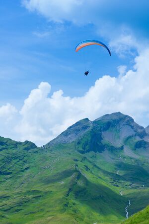 parasailing over the mountains among the cloudsの写真素材