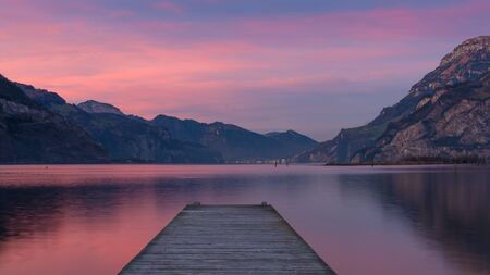 Spectacular sunset over lake in the mountains. Gorgeous colors of clouds reflected in water. long exposureの写真素材