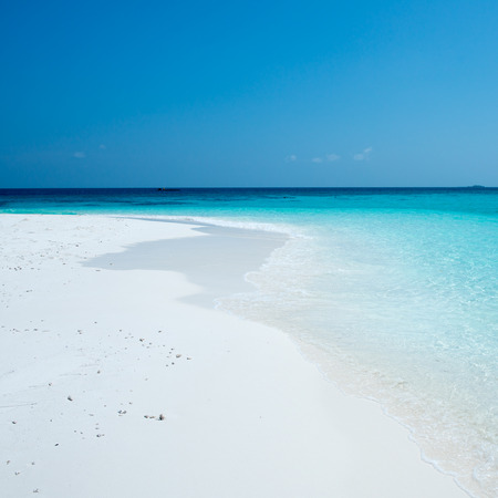Tropical island in the Indian Ocean. White sand beach, blue sky and a strip of oceanの写真素材