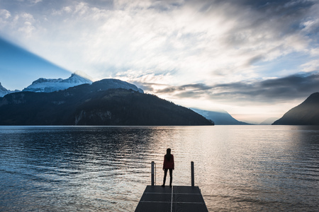 Sunset over the mountain ridge. Lakeside female figure.の写真素材
