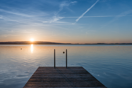 Relaxing quiet evening on the lake. Setting sun is reflected in water. Switzerland.の写真素材