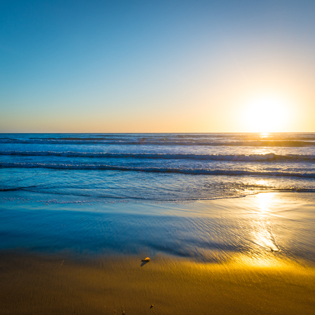 Sunset over the ocean. Sand beach is painted in bright colors in the evening.の写真素材
