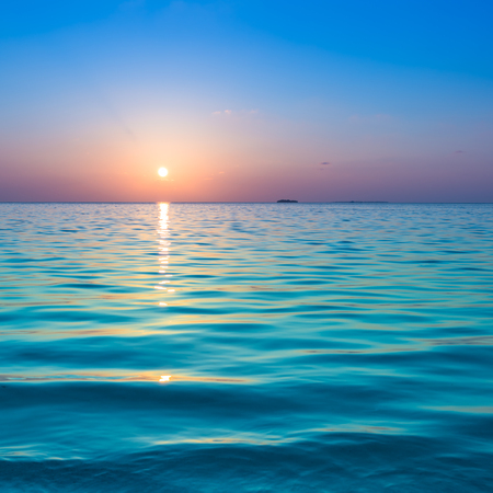 Fantastic color of sunset on a tropical island. Waves on the white sand beach. Relax evening in the Maldives.の写真素材