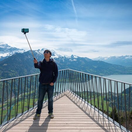 Interlaken, Switzerland - April 30, 2015. Young man photographing himself on a phone, standing on...