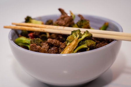 Bowl of beef stir fry with chopsticks on white background.の写真素材