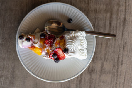 Piece of strawberry and blueberry cake on white plate with spoonの写真素材