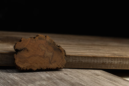 A piece of wood lying on a wooden table. Black background.の写真素材