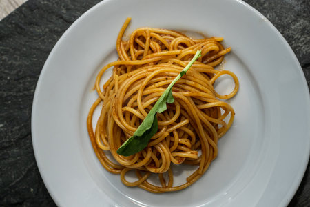 Spaghetti with pesto sauce and arugula on white plateの写真素材