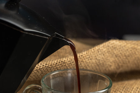 Coffee pouring into a glass cup on a burlap backgroundの写真素材