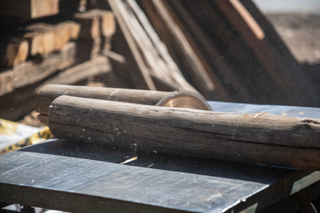 Carpenter using a circular saw to cut a wooden beam.の写真素材