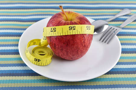 Red apple and yellow measuring tape concept for healthy diet and body weight control.の写真素材