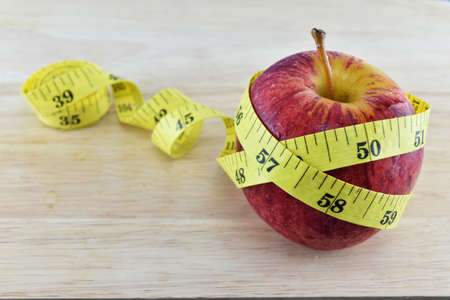 Red apple and yellow measuring tape concept for healthy diet and body weight control.の写真素材