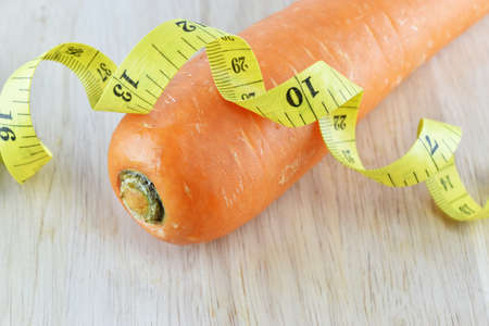 orange carrot and yellow measuring tape on wooden concept for healthy diet and body weight control.の写真素材