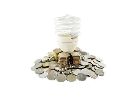 Coins heap with light bulb (energy savings concept) on white background with clipping paths.の写真素材