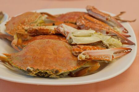 seafood on dish. Fresh sea red crabs boiled in white plate on table in restaurant.