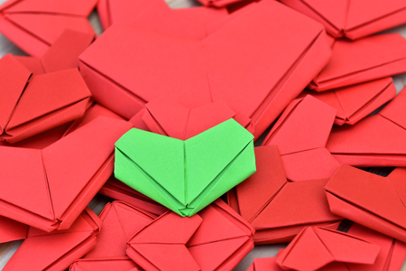 Difference green paper heart shape put on many red paper heart shape background. Concept for Valentines Day background, wedding and take care of your health.の写真素材