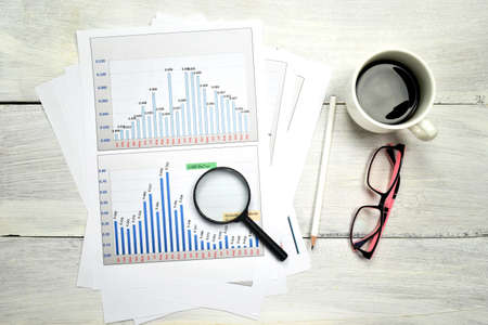 Financial graphs and charts with coffee, glasses, calculator on desk. Business concept.の写真素材