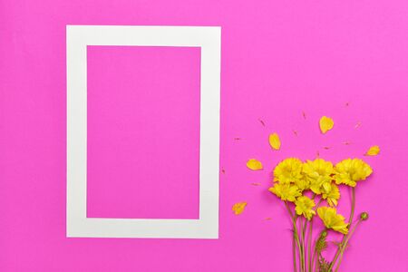 Empty blank photo paper frame with yellow flower on pink background.の写真素材