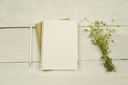 Notebook and dried flower on wood background. top view. copy space.