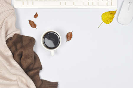Autumn concept. Sweater coat with cup of coffee and laptop, autumn leaves on white background and copy space.の写真素材
