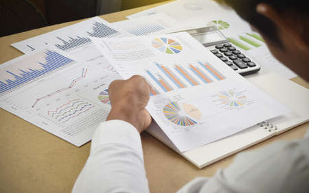businessman working analyzing financial graphs and charts report on desk in office. accounting and...