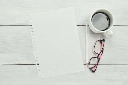 Blank paper mockup with cup of coffee, pencil and glasses on wooden background. Top view. copy...