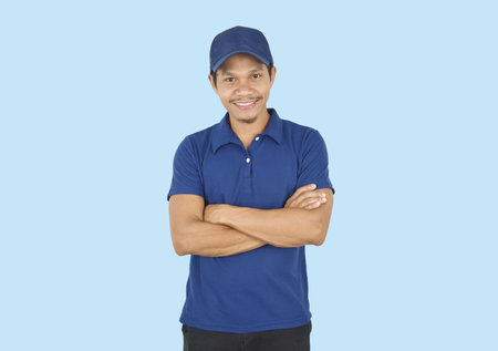 Delivery service concept. Portrait delivery man standing with arms crossed on blue background....